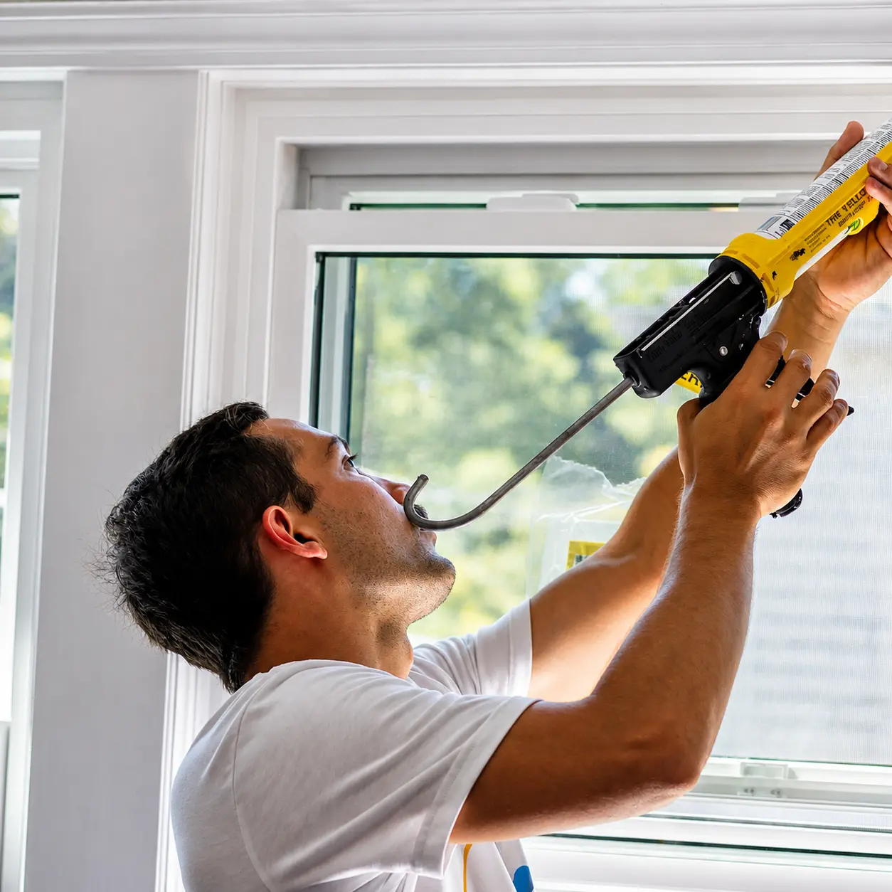 Installer applying caulk while fitting a new window